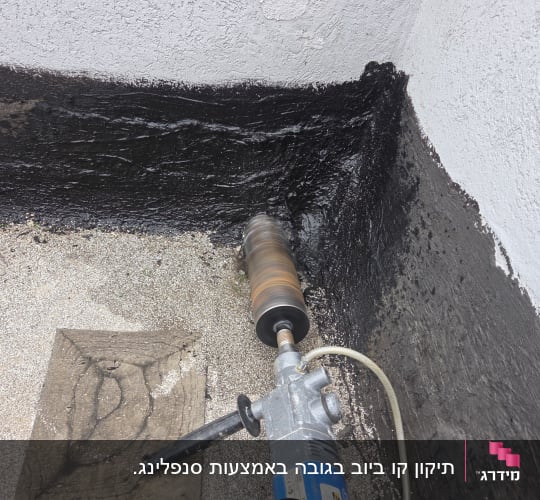 קידוח יהלום בקיר מוטם בחיבור גג ליצירת פתח ניקוז